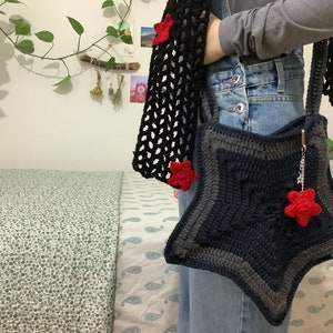 May include: A blue and gray crocheted star-shaped bag with a red star charm. The bag is worn over the shoulder and has a black crocheted strap.