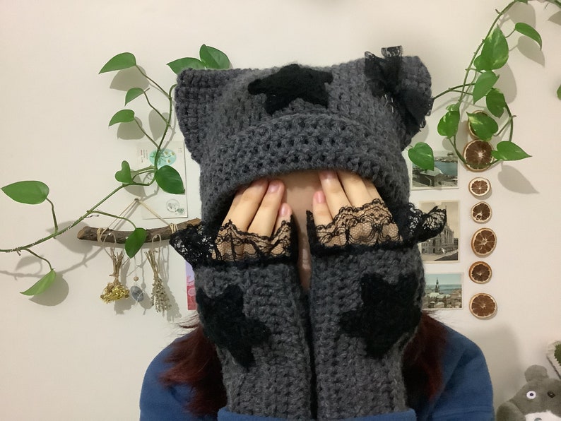 May include: Gray crocheted hat with black star embellishments and matching fingerless gloves with black lace trim.