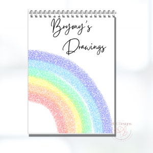 May include: A white drawing book with a rainbow made of colourful dots and the text "Bryony's Drawings" on the cover.