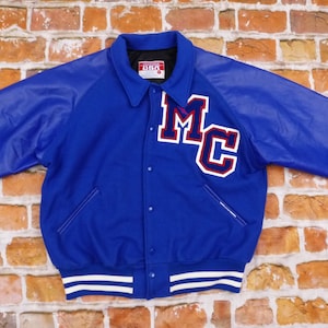 May include: A blue and white varsity jacket with leather sleeves. The jacket has a large "MC" patch on the front.
