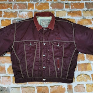 Könnte beinhalten: Ein Set aus drei Keramikbechern mit gesprenkelter, matter Oberfläche. Die Becher sind in Creme-, Hellgrau- und Dunkelgrautönen gehalten. Jeder Becher hat ein schlichtes, minimalistisches Design, ideal für Kaffee oder Tee.