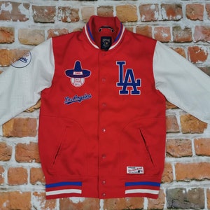 Può includere: Giacca da baseball rossa con maniche bianche e bordini blu e bianchi. La giacca ha un logo dei Los Angeles Dodgers sul davanti e una toppa del All-Star Game del 1963 sulla manica sinistra.