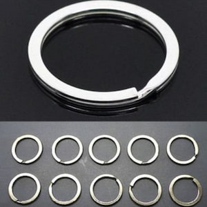 May include: Ten silver key rings, each with a circular shape and a smooth, polished finish.
