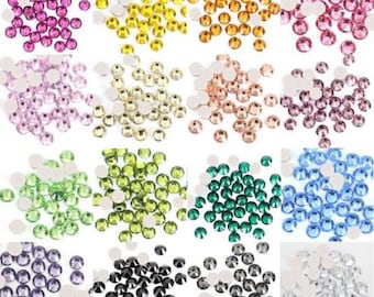 Könnte beinhalten: Sortiment aus 12 Farben runder Strasssteine, jede Farbe in einem separaten Haufen. Die Farben sind: Lila, Gelb, Orange, Hellblau, Rosa, Weiß, Hellgrün, Dunkelgrün, Blau, Lavendel, Schwarz und Klar.