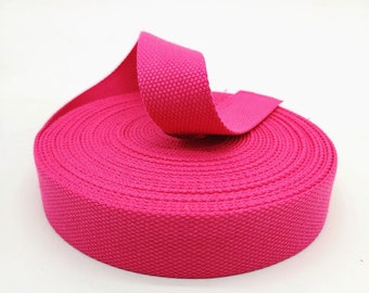 May include: A roll of bright pink cotton webbing, a type of flat woven fabric used for straps, belts, and other craft projects.