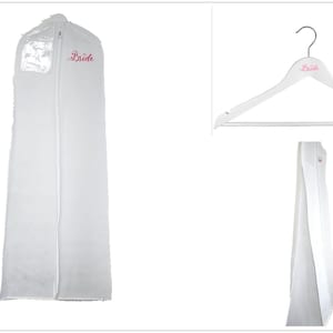 May include: White garment bag with a zipper closure and a clear plastic window. The bag has the word "Bride" embroidered in pink on the front. A white wooden hanger with the word "Bride" printed in pink is also included.