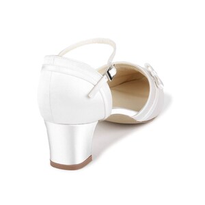 May include: White satin bridal shoes with a low block heel and an ankle strap. The shoes have a satin bow on the toe.