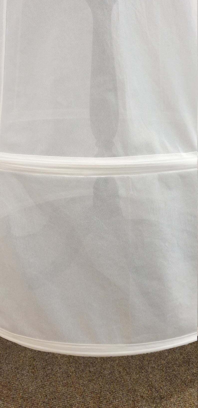 Puede incluir: Bolsa de ropa de malla blanca con una cremallera blanca y un ribete blanco alrededor del borde inferior.