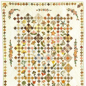 May include: A white quilt with a patchwork design featuring a variety of floral and geometric patterns in shades of brown, green, pink, and yellow. The quilt is surrounded by a border of green leaves and flowers.