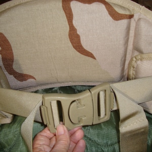 May include: A tan and brown camouflage military-style belt with a plastic buckle. The belt is adjustable and has a padded back.
