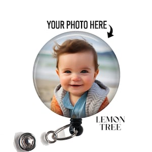 May include: A round, clear badge reel with a photo of a smiling baby. The text "YOUR PHOTO HERE" is above the photo, with an arrow pointing to the image. The text "LEMON TREE" is below the image.