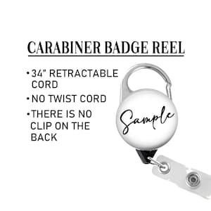May include: A silver carabiner badge reel with a white round button that says "Sample" in black cursive writing. The reel has a 34-inch retractable cord and a white plastic strap with a clear plastic button.