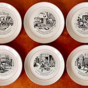 May include: Set of six white ceramic plates with black and white illustrations and red trim. Each plate features a different scene from a story with a corresponding caption.