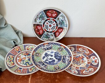 Può includere: Quattro piatti in ceramica decorativi con intricati disegni floreali e geometrici in tonalità di blu, rosso, verde e bianco. I piatti presentano una varietà di motivi, tra cui fiori stilizzati, foglie e forme geometriche.