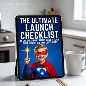 May include: A tablet displays "THE ULTIMATE LAUNCH CHECKLIST" with a child dressed as a superhero. The child wears a red cape and mask, pointing upwards. A white mug and notebook are on the table.
