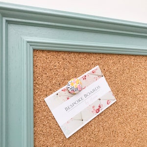 May include: A light blue framed cork board with a business card pinned to it that says "Bespoke Boards by The Maker".