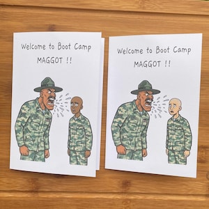 May include: Two greeting cards with the text "Welcome to Boot Camp MAGGOT !!" and a cartoon illustration of a drill sergeant yelling at a recruit. The drill sergeant is wearing a green uniform and hat.