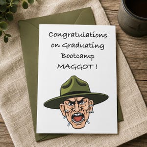Könnte beinhalten: Eine weiße Grußkarte mit schwarzem Text, der Congratulations on Graduating Bootcamp MAGGOT! lautet. Unter dem Text befindet sich eine farbige Illustration eines schreienden Ausbilders, der einen grünen Kampagnenhut mit breiter Krempe trägt.