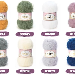 Op de afbeelding: Acht bollen Nako Paris-garen in diverse kleuren: mosterdgeel, olijfgroen, wit, lavendel, grijs, cr&egrave;me, lichtgrijs en marineblauw. Elke bol is voorzien van een uniek nummer.