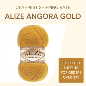 May include: A skein of Alize Angora Gold yarn in a golden yellow colour. The yarn is wrapped around a label that reads "Alize Angora Gold".