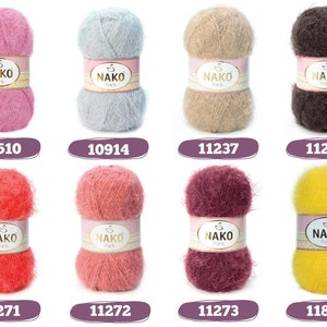 Op de afbeelding: Een verzameling van acht bollen Nako Paris garen in diverse kleuren, waaronder roze, blauw, beige, bruin, rood, koraal, bordeaux en geel. Elke bol heeft een label met de merknaam en een uniek nummer. Het garen ziet er zacht en pluizig uit.
