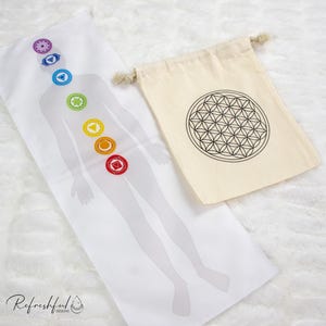 May include: White cotton bag with a black and white flower of life design. A white cotton mat with a human figure and seven colored chakras.