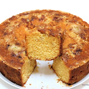 May include: A golden brown cake with a streusel topping. A slice of the cake has been removed, revealing the moist, yellow interior.
