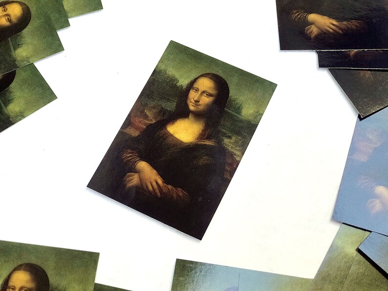 May include: A set of postcards featuring a reproduction of the famous Mona Lisa painting. The postcards are printed on high-quality cardstock and feature a glossy finish.