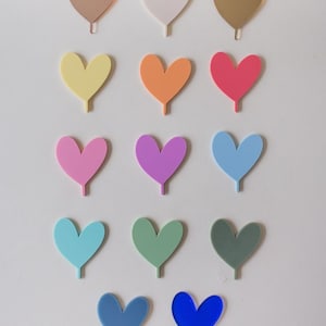 May include: A set of 15 heart-shaped acrylic toppers in various colors, including rose gold, white, gold, yellow, orange, red, pink, purple, light blue, teal, green, gray, blue, and royal blue. The toppers are perfect for adding a touch of whimsy to cakes, cupcakes, or other desserts.