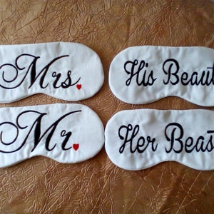 Peut inclure: Quatre masques de sommeil blancs avec des broderies noires. Les masques disent "Mrs." avec un cœur rouge, "Mr." avec un cœur rouge, "His Beauty" et "Her Beast".