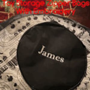 May include: Black round toy storage bag with white embroidery that says "James".