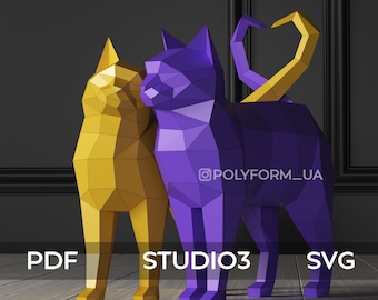 Könnte beinhalten: Zwei Papier-Katzen, eine gelbe und eine violette, stehen auf einem Holzboden. Die violette Katze hat ihren Schwanz zu einem Herz geformt. Der Text "STUDIO3" ist auf dem Boden sichtbar.
