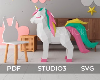 May include: A white papercraft unicorn with pink, green, and yellow accents stands on a wooden floor. The unicorn is in a room with a gray wall decorated with white and pink clouds and gold stars. A white papercraft bunny chair is in the foreground. The text "STUDIO3" is printed on the floor.