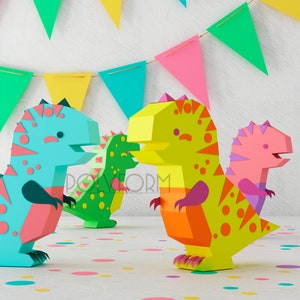 May include: Three papercraft dinosaurs in blue, green, and pink with yellow, orange, and purple accents. The dinosaurs are standing on a white surface with confetti.