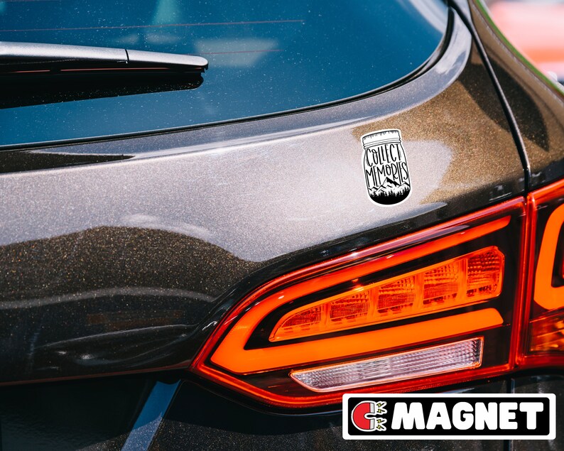 Puede incluir: Un coche negro con una pegatina blanca en la parte trasera. La pegatina es un tarro de cristal con las palabras "Collect Memories" escritas en &eacute;l. El coche tiene una luz trasera roja y una etiqueta negra "MAGNET" en la parte inferior.