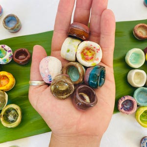 May include: A collection of small, colorful ceramic bowls with various patterns and designs. The bowls are hand-painted and have a unique, rustic look.