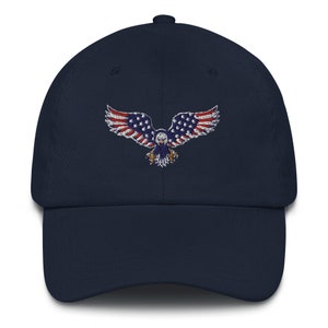 May include: A navy blue baseball cap with an embroidered eagle design. The eagle's wings are red and white striped, with a blue body and stars, resembling the American flag. A classic, adjustable hat.