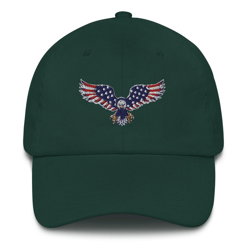 May include: A dark green baseball cap with an embroidered eagle design. The eagle's wings are decorated with the stars and stripes of the American flag. The cap has a curved peak and an adjustable fabric strap.