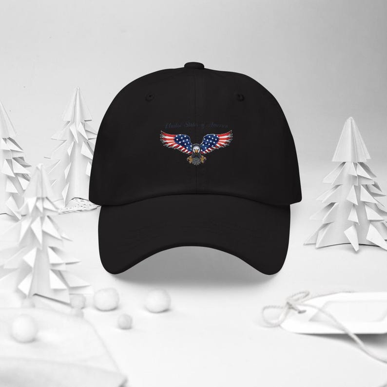 Puede incluir: Gorra de b&eacute;isbol negra con un dise&ntilde;o bordado de un &aacute;guila con alas con los colores de la bandera estadounidense. El texto "United States of America" est&aacute; arqueado sobre el &aacute;guila. La gorra tiene una visera curva y una correa ajustable.