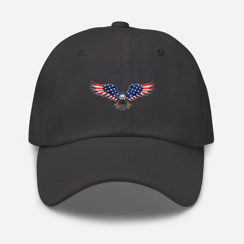 Puede incluir: Gorra de b&eacute;isbol gris oscuro con un dise&ntilde;o de &aacute;guila de la bandera estadounidense. Las alas del &aacute;guila son de rayas rojas y blancas, con estrellas azules. El cuerpo del &aacute;guila est&aacute; detallado con plumas marrones y blancas.