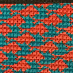 以下が含まれることがあります： 赤と青のクロスステッチのパターンのクローズアップ。パターンは小さな正方形で構成されており、色は繰り返しのパターンで配置されています。