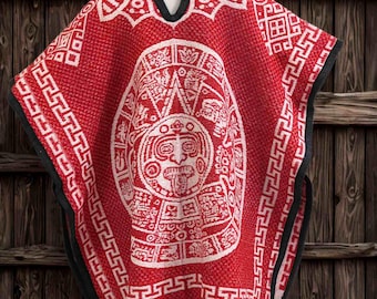 May include: A red poncho with a white Aztec calendar design and geometric patterns. The poncho has a black trim and fringe along the bottom. It is displayed on a white mannequin against a wooden background.