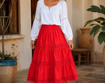 Op de afbeelding: Een witte blouse met lange mouwen, een ronde halslijn, kanten afwerking en een striksluiting, gecombineerd met een felrode midirok met een gelaagd ontwerp en horizontale kanten details. De rok heeft een elastische tailleband.