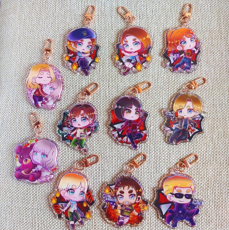 K&ouml;nnte beinhalten: Eine Sammlung von elf Acryl-Schl&uuml;sselanh&auml;ngern mit Chibi-Anime-Figuren in verschiedenen Haarfarben, Outfits und Accessoires, jeweils mit einem goldfarbenen Karabinerhaken versehen und in einem Raster auf einer strukturierten beigen Oberfl&auml;che angeordnet.