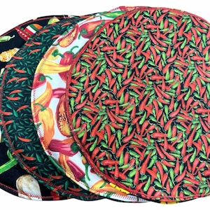 May include: Four circular fabric placemats with vibrant chili pepper and food designs. The placemats display various patterns, including red and green chili peppers on a black backdrop, and other food-related graphics.