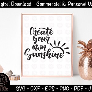 Peut inclure: Une impression encadrée avec les mots "Create your own Sunshine" en écriture noire. L'image comprend un ananas décoratif et des rouleaux de ruban adhésif. Le bas de l'image affiche les options de type de fichier: SVG, DXF, EPS, PNG, PDF et JPG.