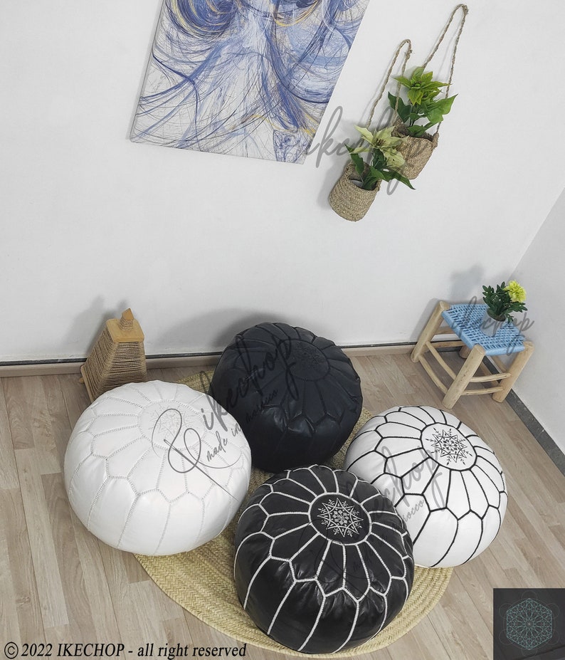 May include: Four poufs, two black and two white, with intricate stitching and a star design in the center. The poufs are arranged on a woven rug.