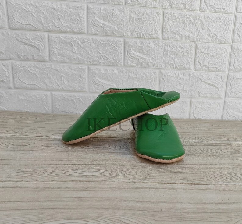 Puede incluir: Un par de zapatillas de cuero verde. Las zapatillas son de punta y tienen un dise&ntilde;o sencillo.