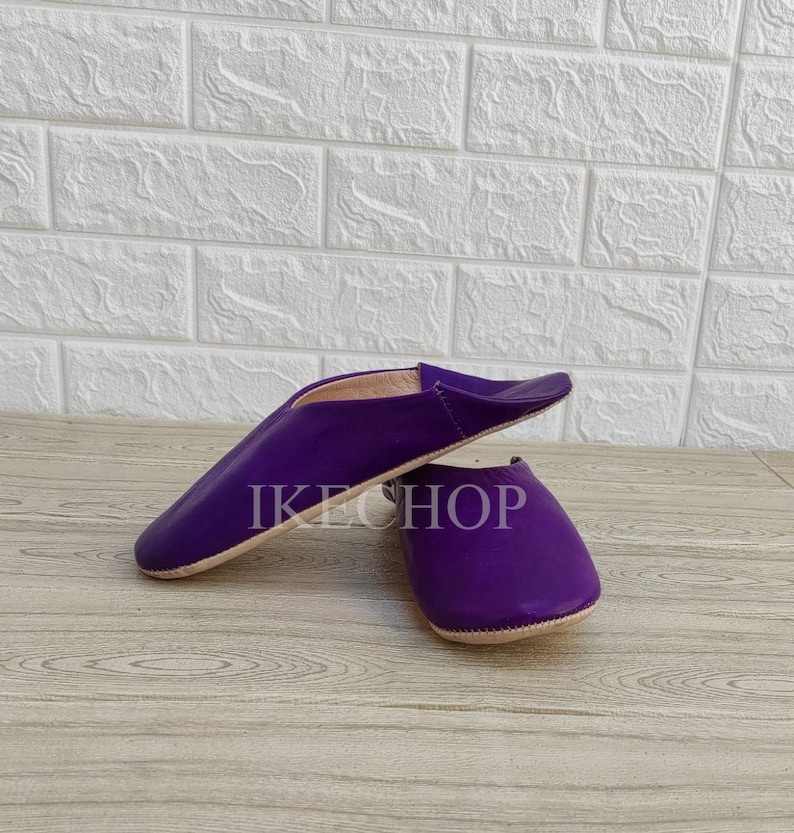 Puede incluir: Un par de zapatillas de cuero morado con punta puntiaguda y suela plana. Las zapatillas est&aacute;n hechas de cuero suave y tienen un ajuste c&oacute;modo.
