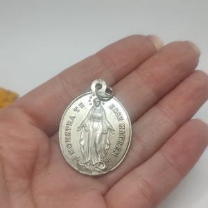 May include: Silver pendant featuring a depiction of the Virgin Mary with the text "MONSTRA TE ESSE MATREM" around the edge.
